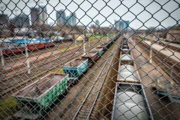 Railway station, trains, wagons. View through the steel wire fence.