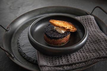 Tatar roh vom Rind mit schwarzen Kaviar, Schmand und Brot als Gourmet Rindertatar auf dunkel Teller und Hintergrund