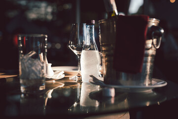 Still life of empty wine glasses and wine bottle in bucket with bottle of mineral water arranged on table.