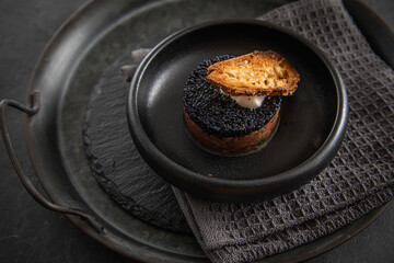 Tatar roh vom Rind mit schwarzen Kaviar, Schmand und Brot als Gourmet Rindertatar auf dunkel Teller und Hintergrund