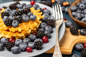 Berries, waffles and a fork on a gray plate. Berries on the table.