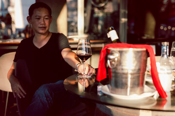 Happy asian man drinking red wine in restaurant.