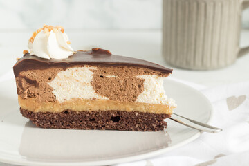 Piece of chocolate mousse cake with whipped cream on top, served on white plate