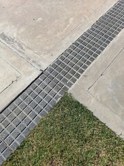 Fototapeta premium El suelo del jardín del parque de la ciudad con baldosas a cuadros de hormigón gris formando un triángulo con la hierba, forma un diseño texturado original para los fondos