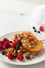 Tasty bowl of fresh fruits, granola and yogurt. Healthy snack served for one on a white plate, top view