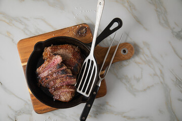 Entrecote Steak vom Rind medium rare gebraten in Gusseisen Pfanne mit Meersalz auf Holzbrett mit...