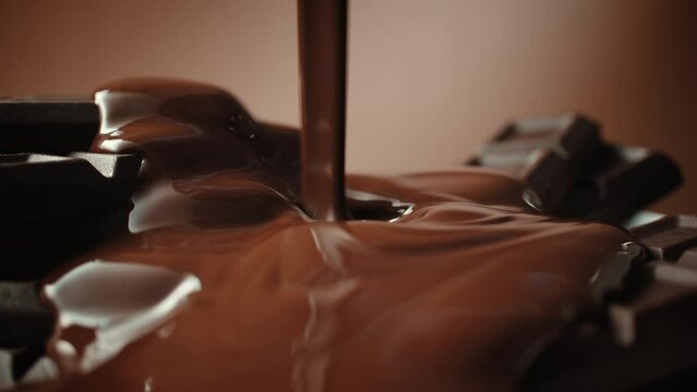 Close-up broken chocolate bar poured with liquid chocolate sauce, lot of homemade chocolate bars and pouring milk chocolate. Handmade, confectionery manufacture
