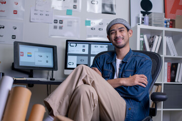 Portrait of Asian man graphic designer sitting and smiling while looking at camera.
