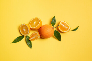 Orange fruit top view with slices on yellow background.
