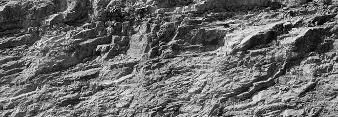 Grungy cragged bumpy pitted cavity stone facade, split layer gap.Ruined cracked shattered worn rough hiking canyon.Old ragged grunge steep marble cliff. Grand vintage crannied damaged impressive gorge