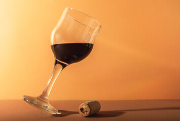 A glass of red wine and a cork from a wine bottle.