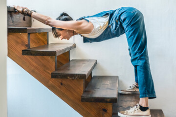 A woman doing stretching exercises on the stairs of her home..