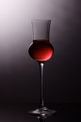 liquor glass with with red liquid and grey shadowed background
