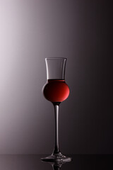 liquor glass with with red liquid and grey shadowed background