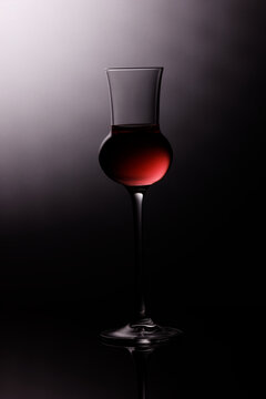 liquor glass with with red liquid and grey shadowed background