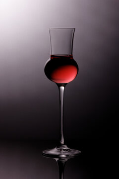 liquor glass with with red liquid and grey shadowed background