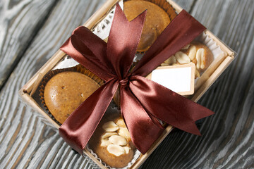 Homemade caramel. Brown caramel candies. Creamy sweets with peanuts. On pine boards. Packed in a box and tied with a ribbon.