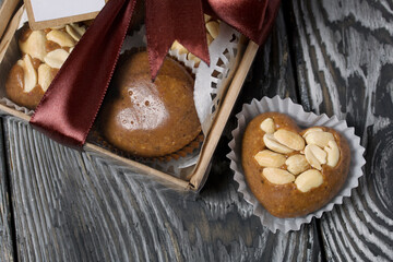 Homemade caramel. Brown caramel candies. Creamy sweets with peanuts. On pine boards. Some of them are packed in a box and tied with a ribbon.