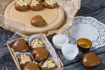 Homemade caramel. Brown caramel candies. Creamy sweets with peanuts. On pine boards. Some of them are packed in a box.