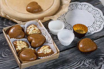 Homemade caramel. Brown caramel candies. Creamy sweets with peanuts. On pine boards. Some of them are packed in a box.