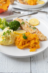 Fish fillet with mashed potatoes and red kuri squash puree. Served with broccoli on a plate