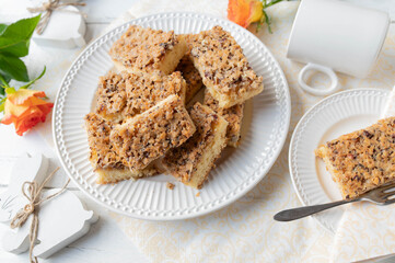Hazelnut cake with caramelized nut topping. Served  sliced on a white plate with easter decoration on white background