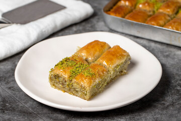 Baklava with pistachio on a dark background. Traditional Turkish baklava in a plate. Studio shoot. close up
