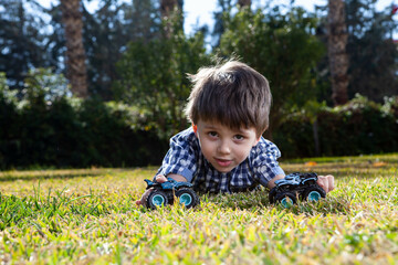 Boy is playing a cars multitrack on the garden 