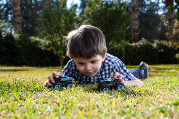 Boy is playing a cars multitrack on the garden 
