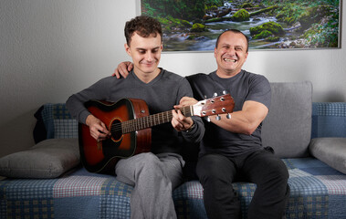 Happy father with his son playing guitar
