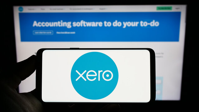 Stuttgart, Germany - 12-30-2022: Person holding smartphone with logo of New Zealand software company Xero Limited on screen in front of website. Focus on phone display.