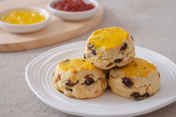 Raisin scones on white plate and jam.
