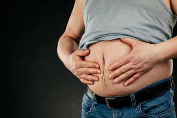 a fat man checking his weight on a black background.