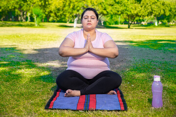 Overweight indian woman doing yoga meditation exercise outdoors in park. Asian Fat lady Fitness lifestyle. Full length shot.