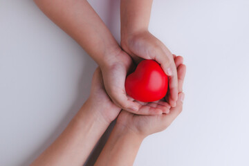 Woman's hand hold kids hand supporting with red heart take care and protection donation from parent, family help together children adoption characteristics. Love concept I love you Mom.