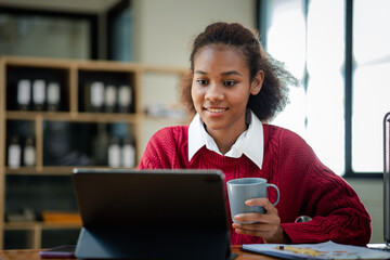 American teenage woman sitting in office with laptop, she is a student studying online with laptop at home, university student studying online, online web education concept.