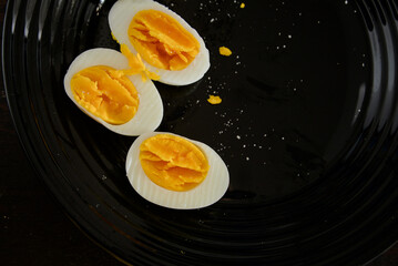 boiled eggs cut in half on black plate

