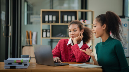Two American women are working together in the office of a startup company. They are having a brainstorming and planning meeting in a joint department, women leading the way. Concept of women's work.