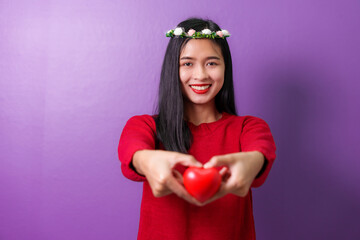 Portrait of pretty asia cheerful lady arms hold heart ball toothy smile isolated on violet color background, for valentine day color tone