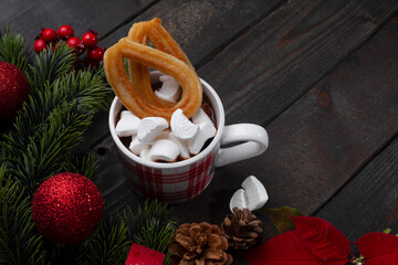 Red mug with hot chocolate on top of which pieces of marshmallows and churros, top view copy space