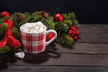 Red mug with hot chocolate on top of which pieces of marshmallows float, with copy space