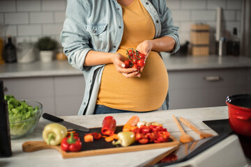 Young woman in kitchen. Beautiful pregnant woman making salad