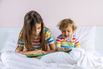 Children read a book in bed. Selective focus.