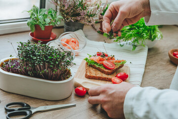 Closeup of man cutting microgreens of radish making sandwich