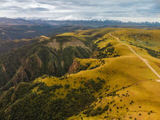 Mountain peaks covered with snow at the top and dry grass below and with clouds descending on the...
