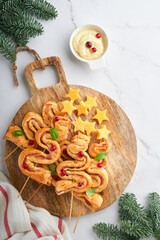 Christmas or New Year appetizer. Christmas tree shape puff pastry buns with cheese and ham. Group of Christmas tree shapes on wooden board. Festive idea for Christmas or New Year dinner. Top view.
