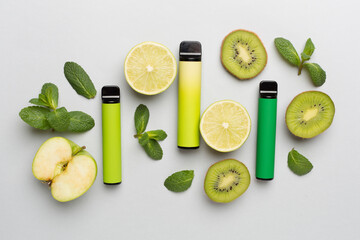 Disposable electronic cigarettes with fruits on color background, top view