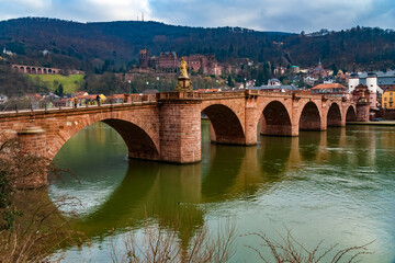 Nice view of Heidelberg's arch bridge Karl-Theodor-Brücke or Alte Brücke (Old Bridge) with its gate and two towers over the Neckar river. In the background is the castle ruin Heidelberger Schloss. 