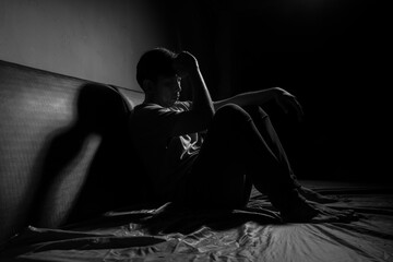 Man with depression sitting in a dark room.  Depression is a low mood that lasts for a long time,...