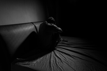 Man with depression sitting in a dark room.  Depression is a low mood that lasts for a long time,...